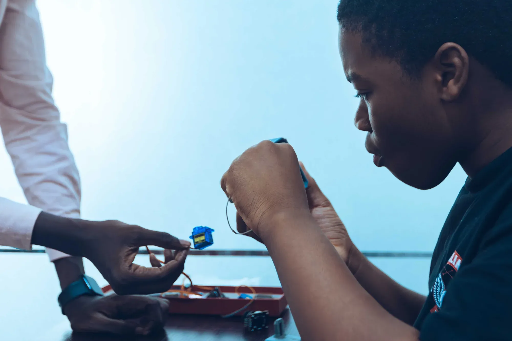 A student assembling electronic components during a hands-on technology workshop; illustrative stock photograph.